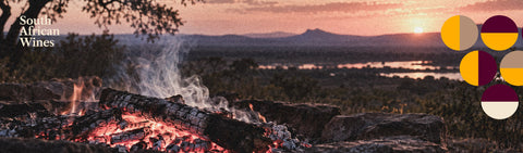 Glutbett mit Rauch im Abendlicht, Berge im Hintergrund, Schriftzug South African Wines